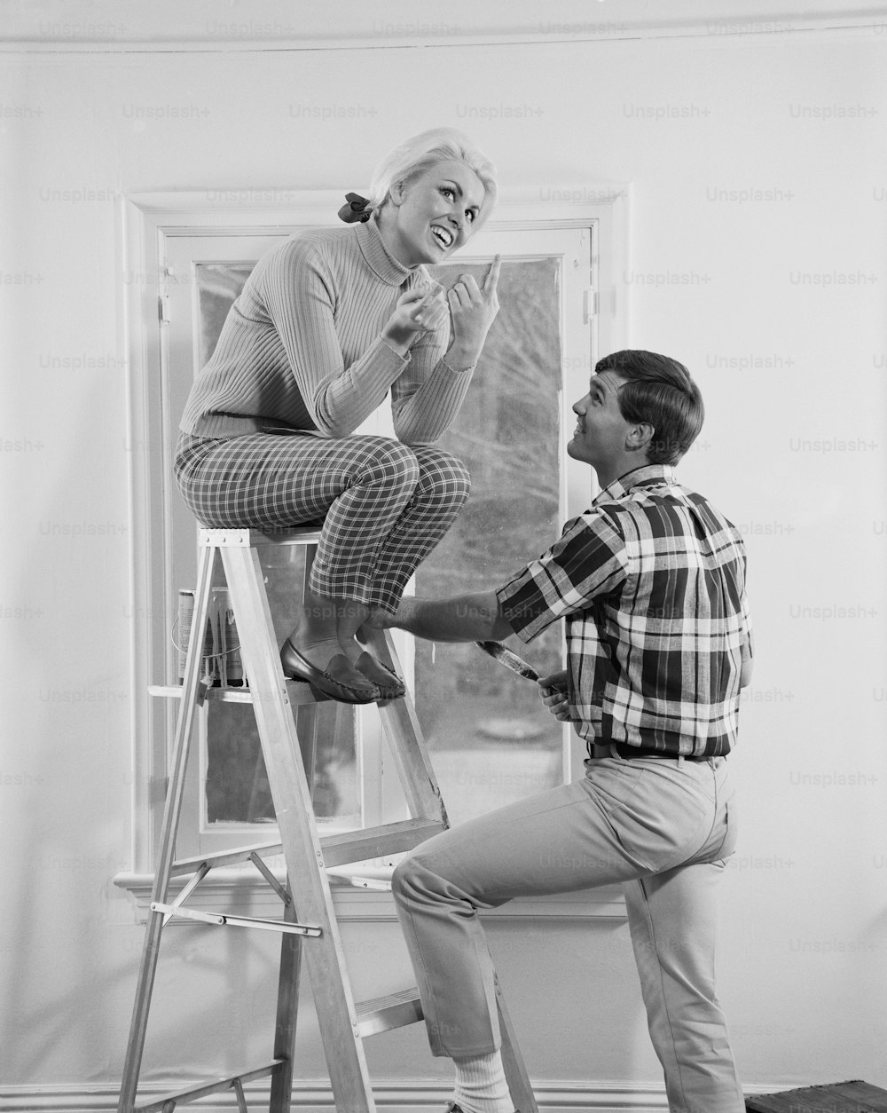 a man standing on a ladder next to a woman