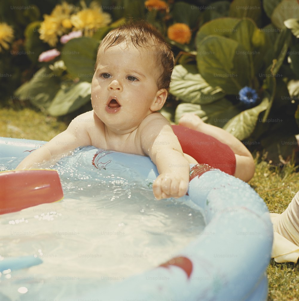 a baby in an inflatable pool playing in the grass