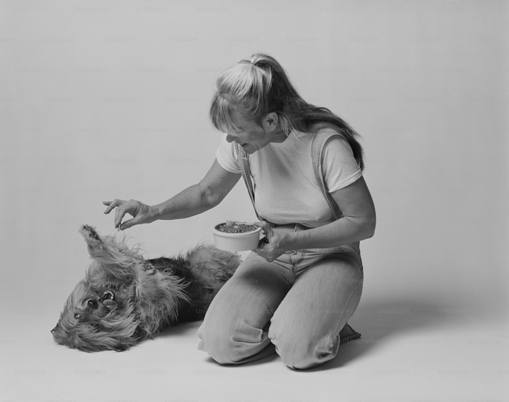Una foto in bianco e nero di una donna che nutre un cane