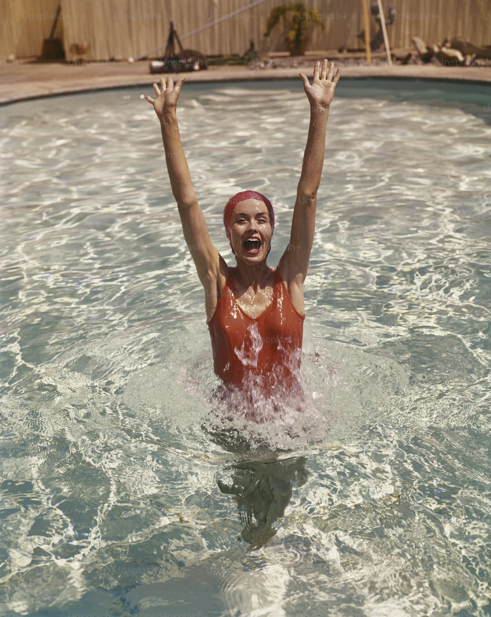 uma mulher em uma piscina com os braços no ar