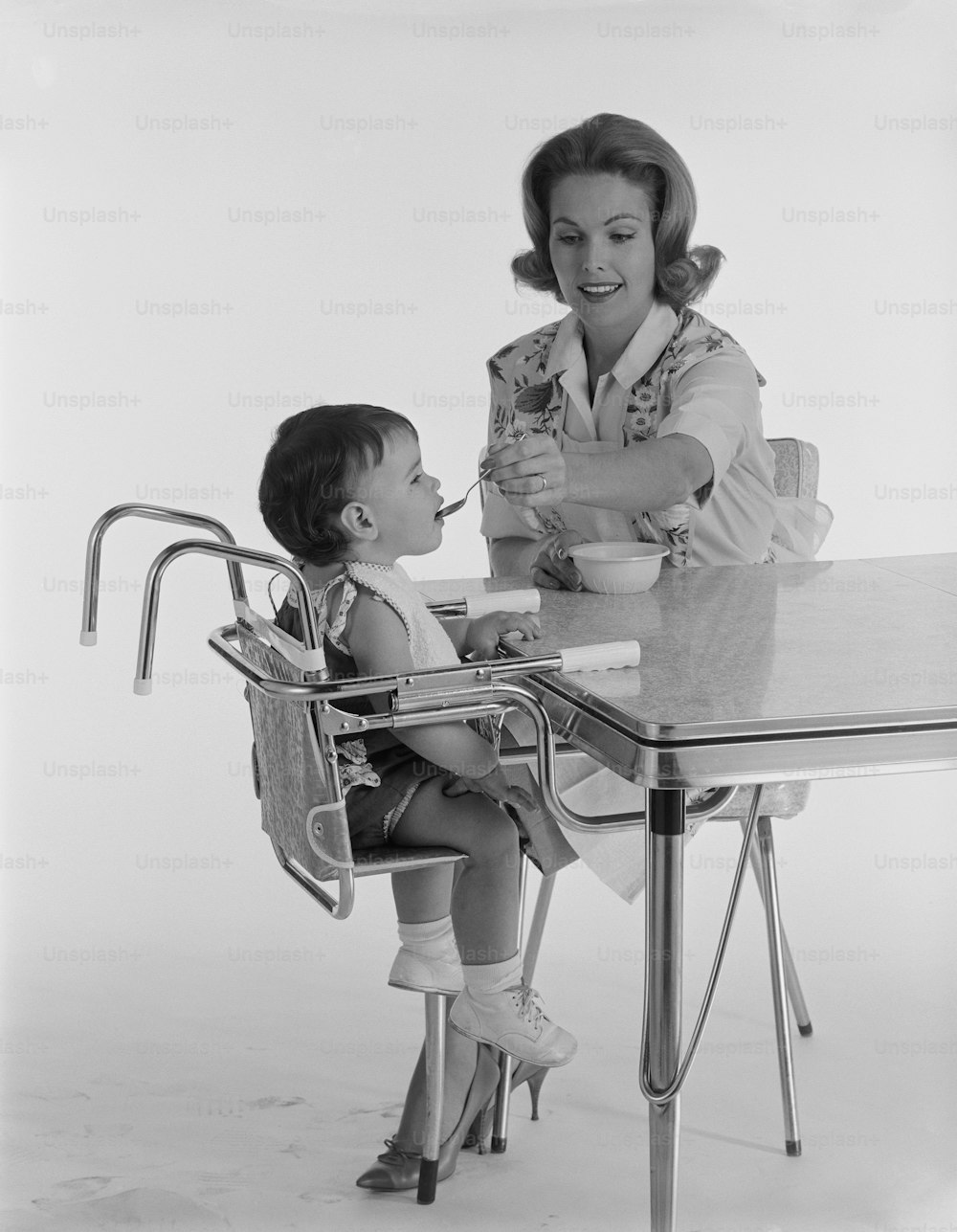 a woman sitting at a table feeding a small child