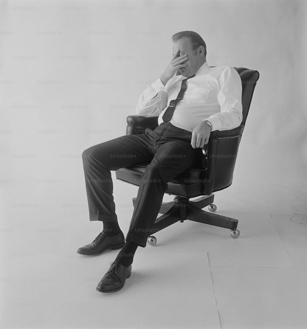 Ein Schwarz-Weiß-Foto eines Mannes, der auf einem Stuhl sitzt