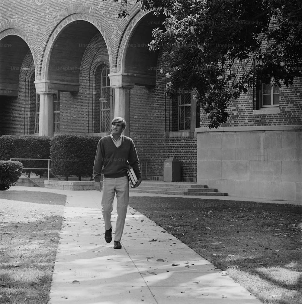 a man walking down a sidewalk in front of a building
