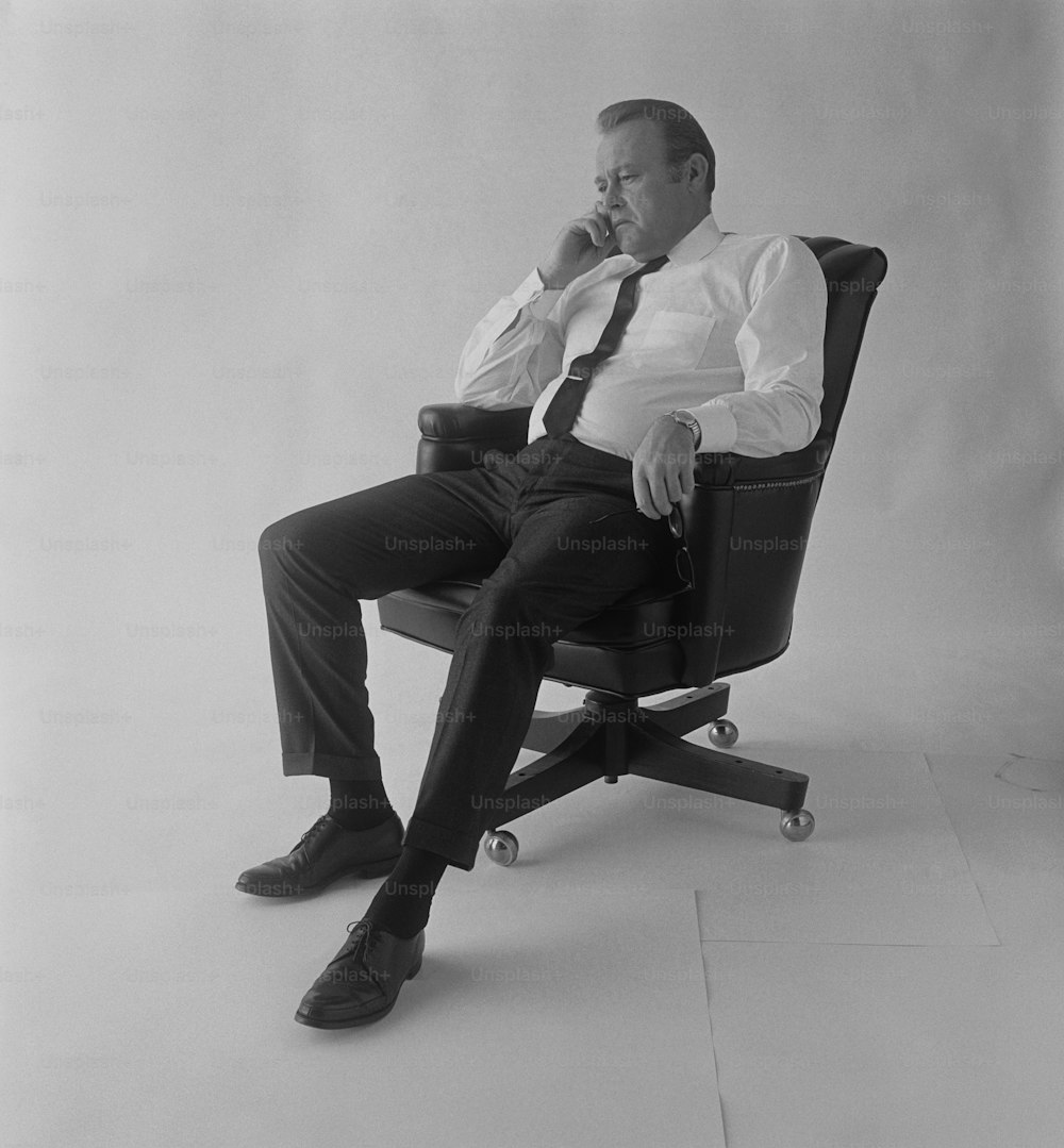 ein Schwarz-Weiß-Foto eines Mannes, der auf einem Stuhl sitzt