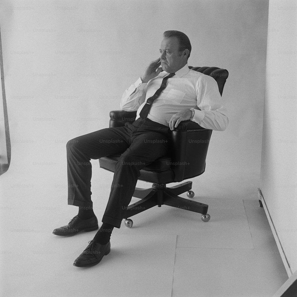 Un uomo seduto su una sedia che fuma una sigaretta
