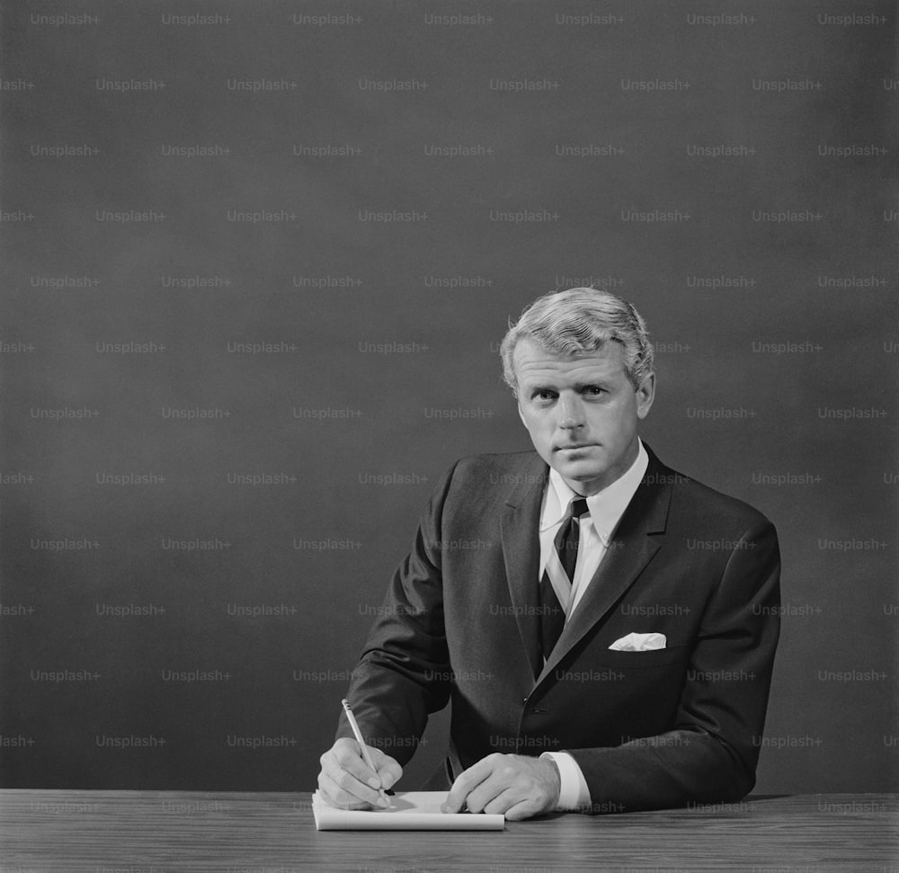 a black and white photo of a man in a suit writing