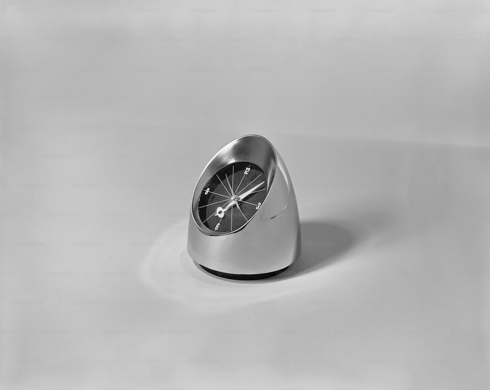 um relógio de prata sentado em cima de uma mesa branca