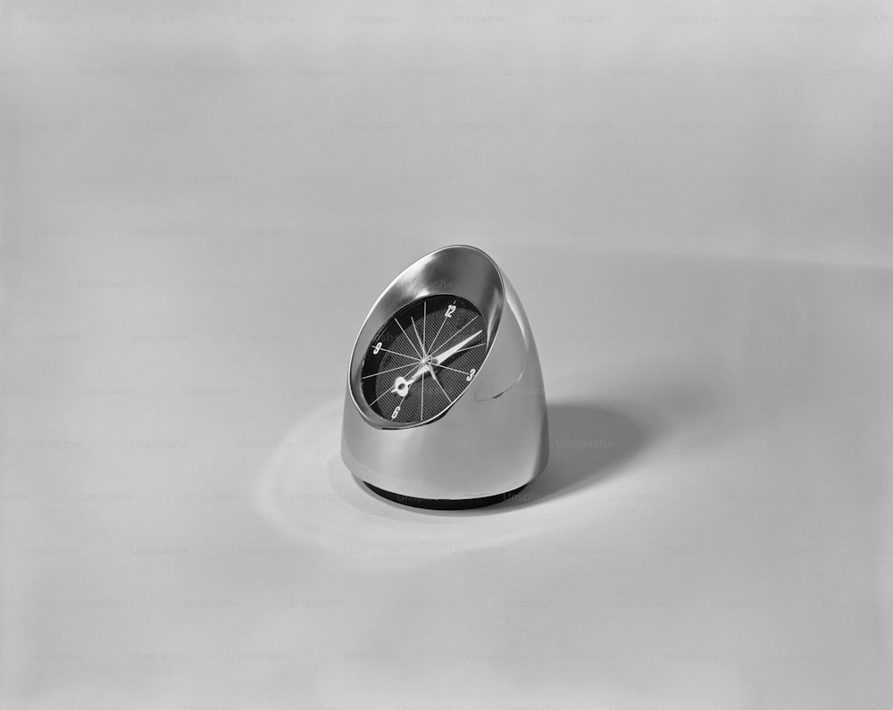 a silver clock sitting on top of a white table