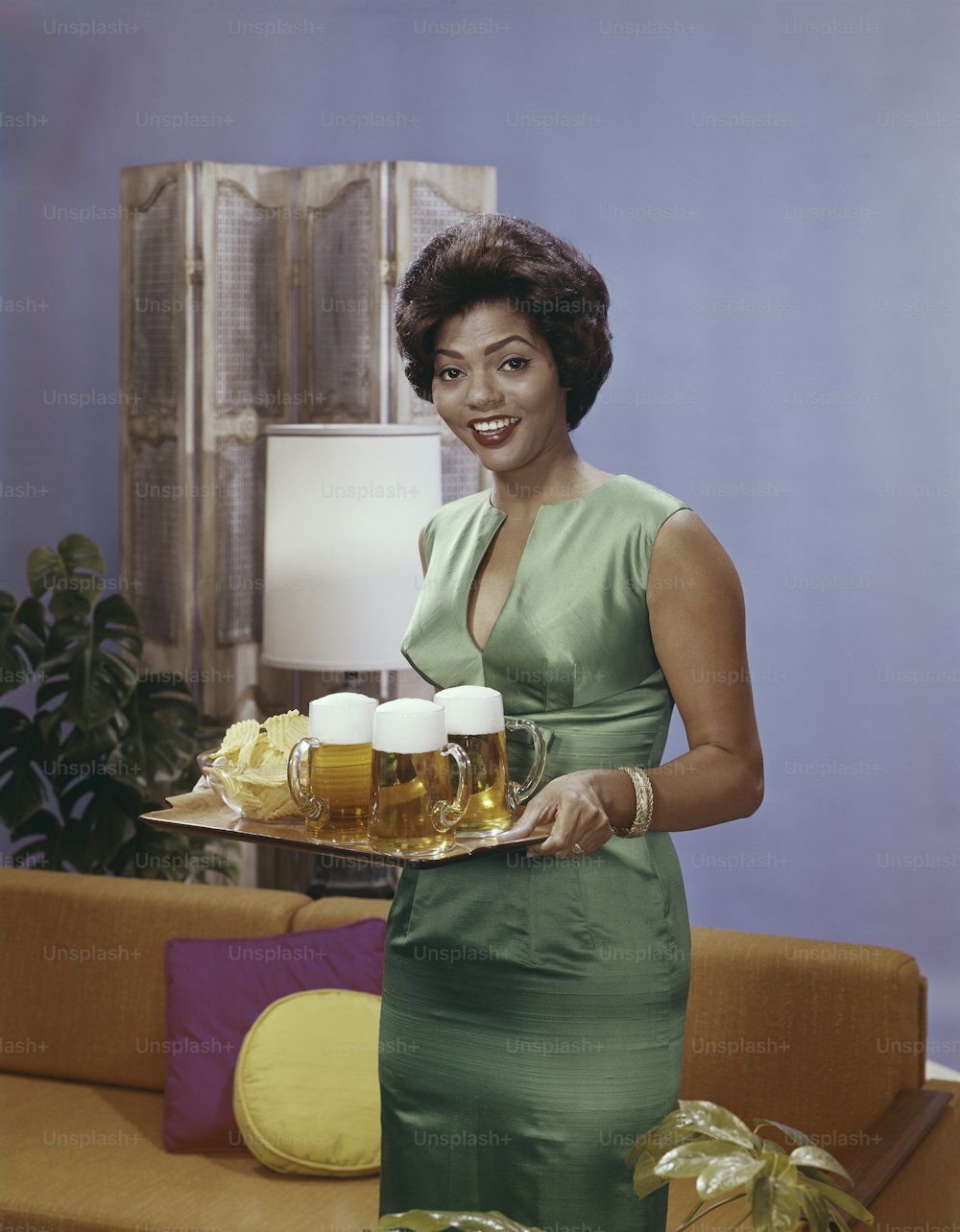 a woman in a green dress holding a tray of beer