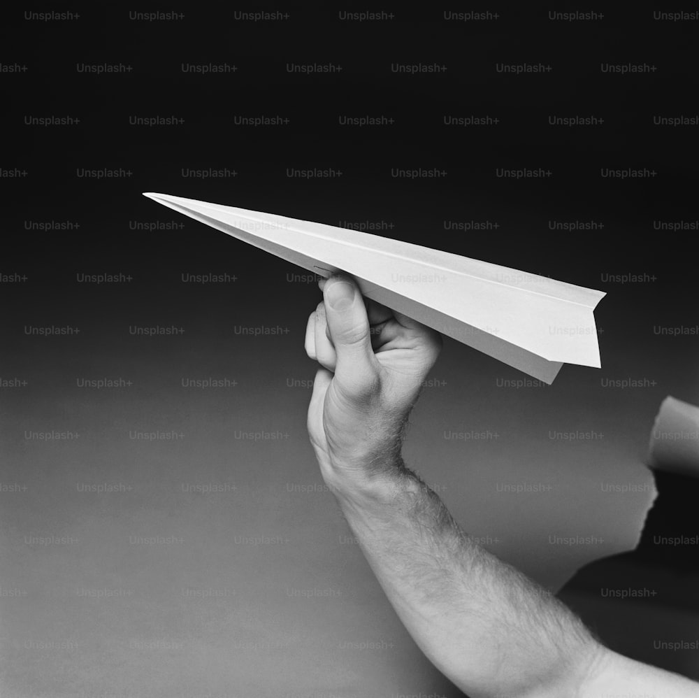 Un hombre sosteniendo un avión de papel en la mano