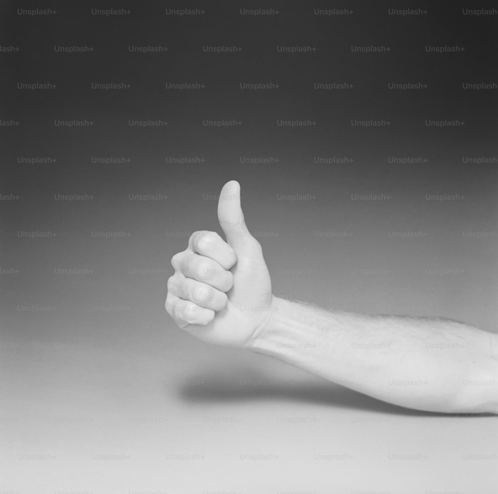 a black and white photo of a hand giving a thumbs up