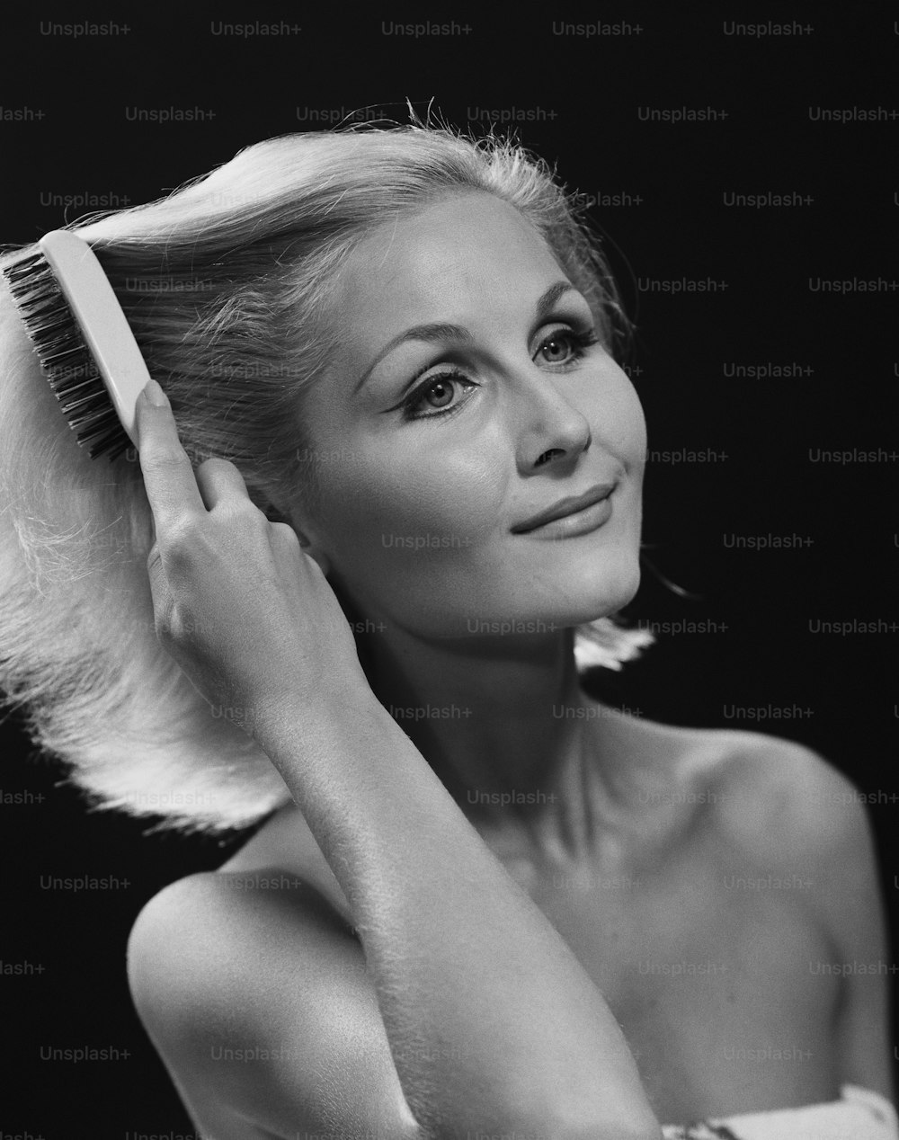 uma foto em preto e branco de uma mulher escovando o cabelo