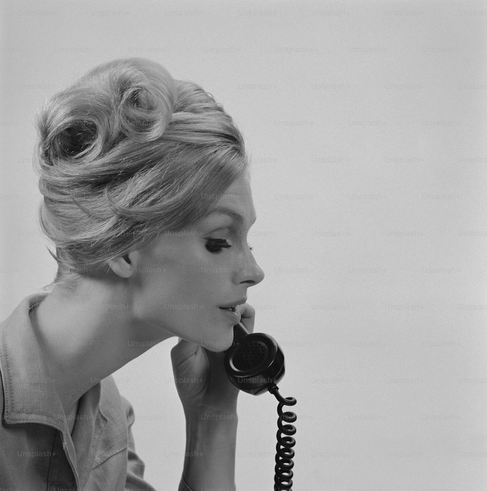 a woman talking on a telephone while holding her hand to her ear