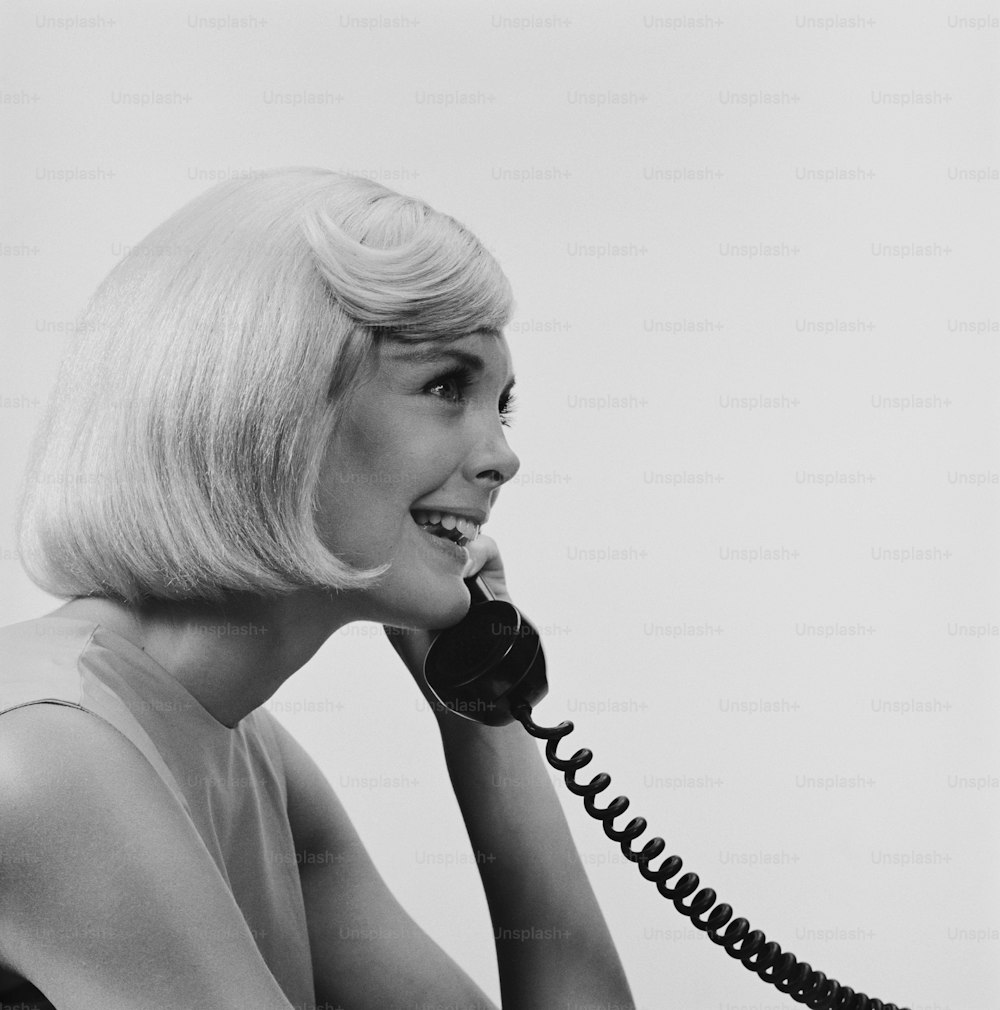 a black and white photo of a woman talking on a telephone