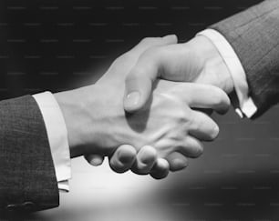 two people shaking hands in a black and white photo