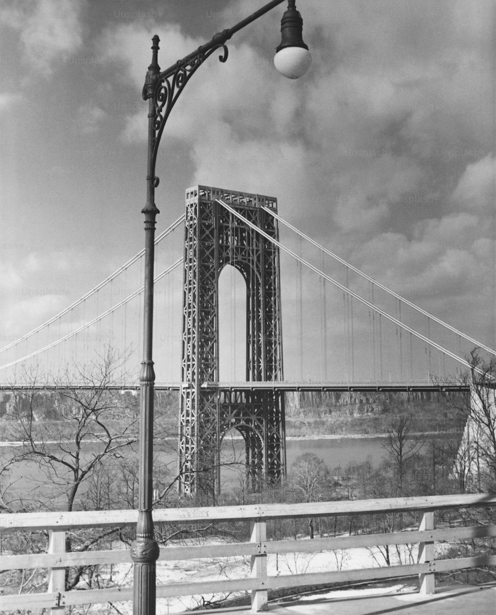 a black and white photo of a street light and a bridge