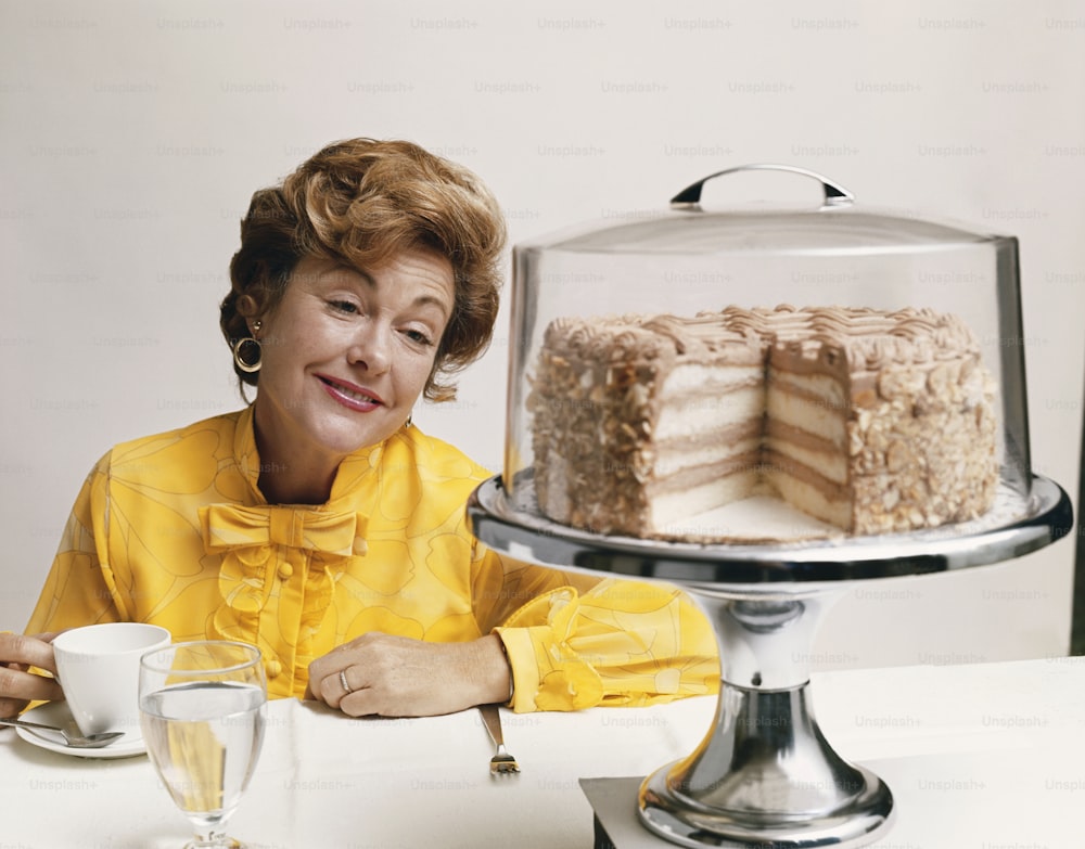 a woman sitting at a table in front of a cake