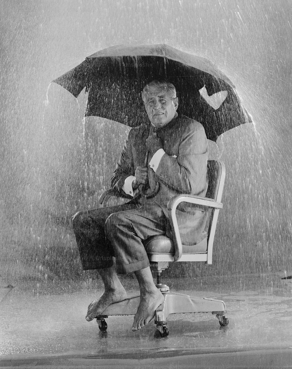 um homem sentado em uma cadeira sob um guarda-chuva