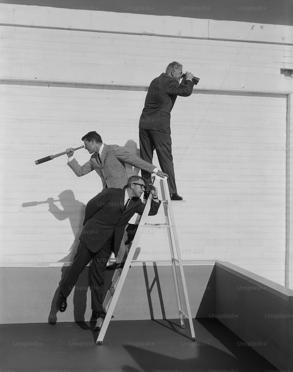 a black and white photo of two men on a ladder