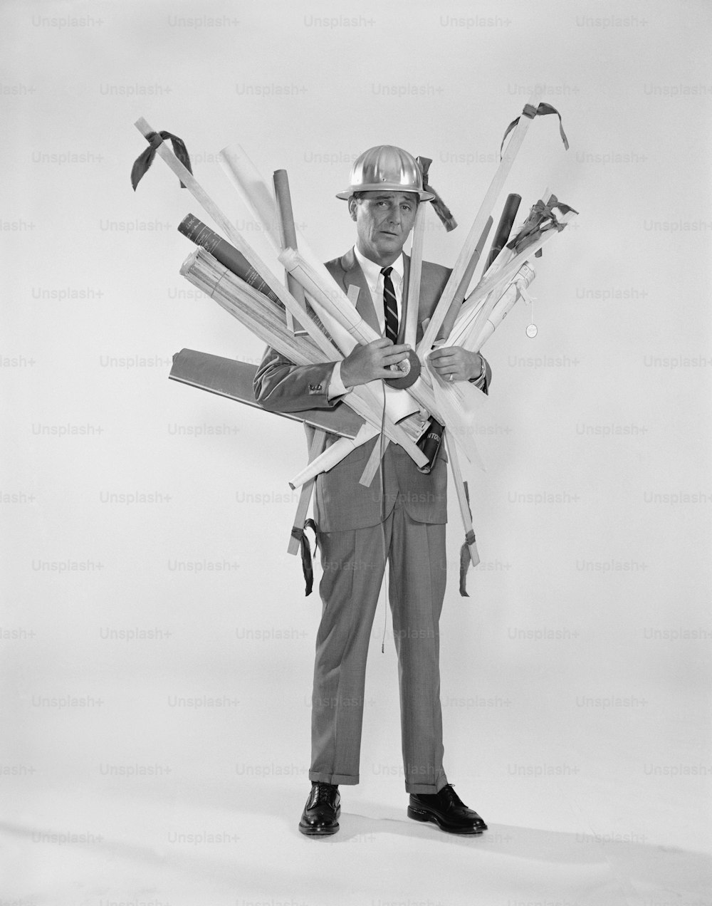 a black and white photo of a man holding a bunch of tools
