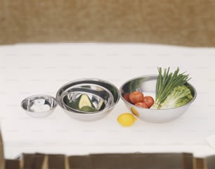 a white table topped with metal bowls filled with food