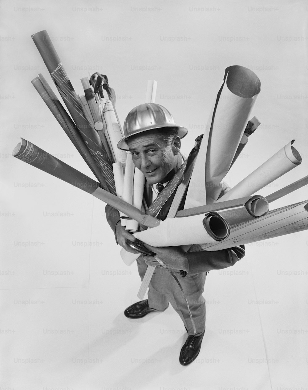 a black and white photo of a man holding a bunch of baseball bats