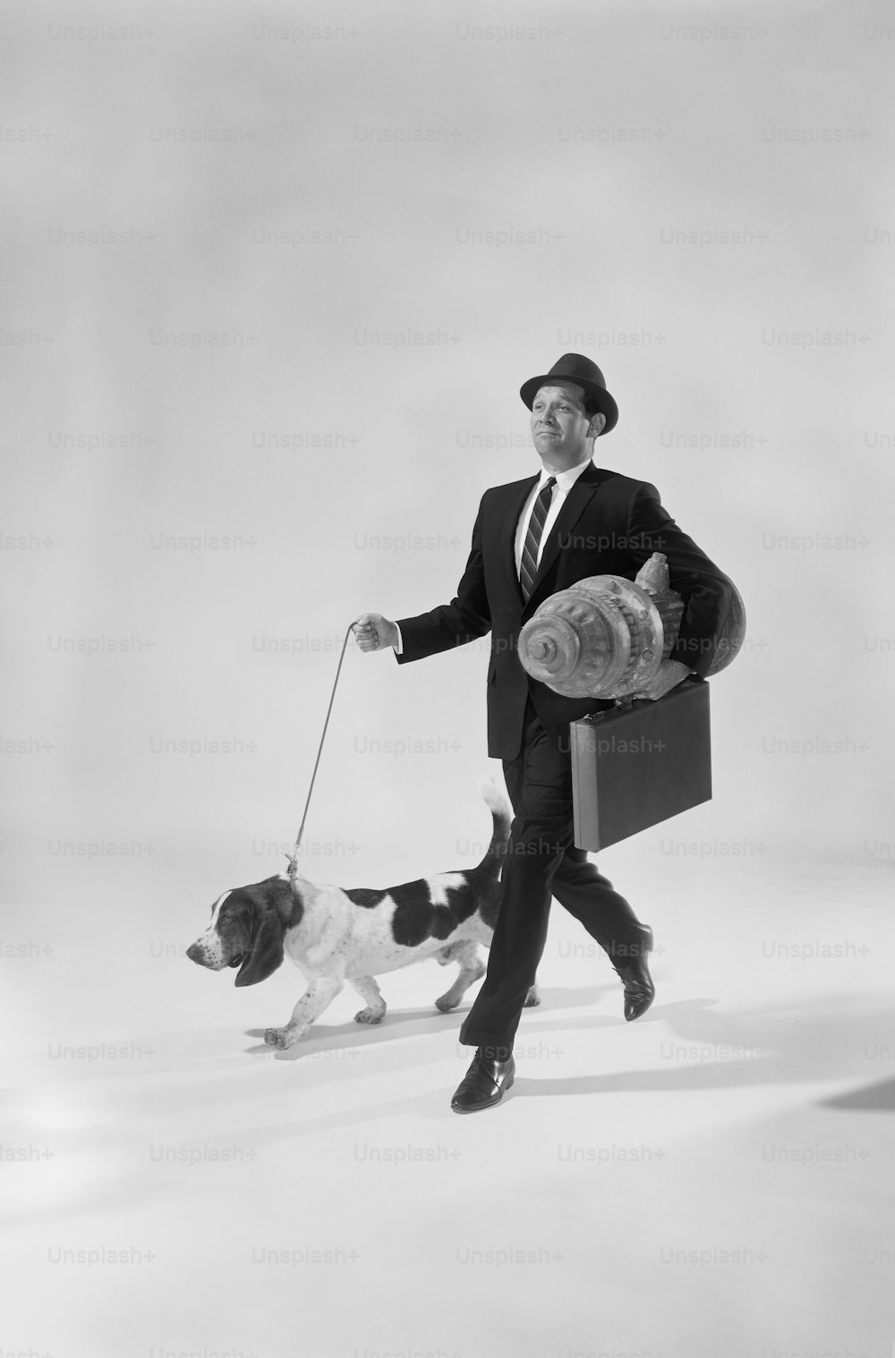 a man in a suit and tie walking a dog