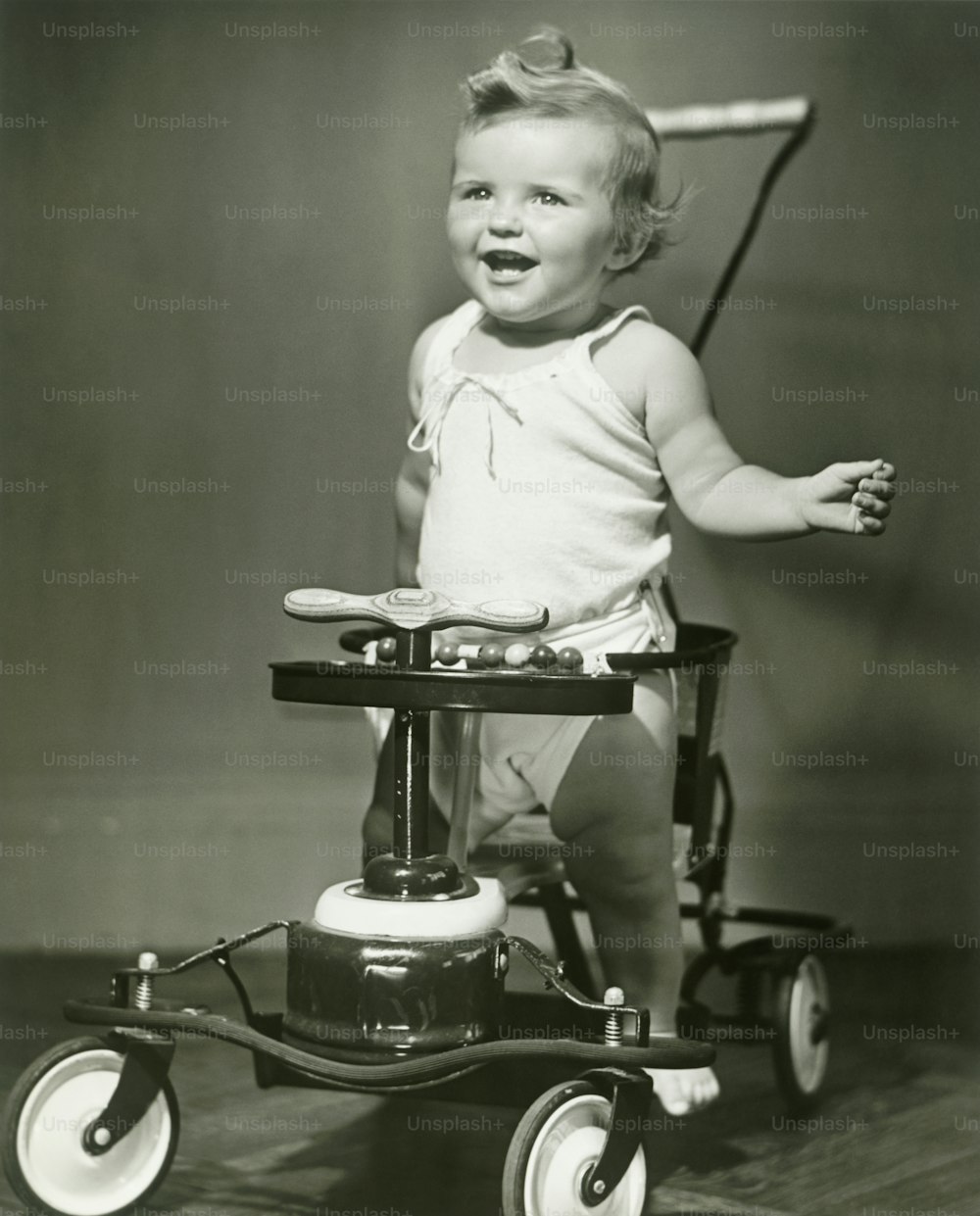 Una bambina in un pannolino che cavalca un triciclo