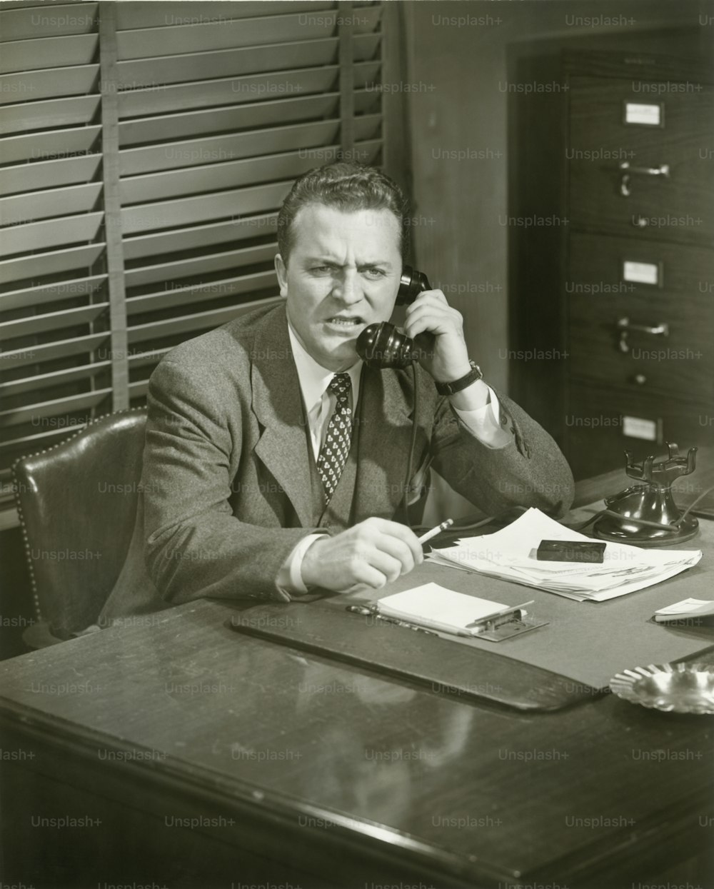 um homem sentado em uma mesa falando ao telefone