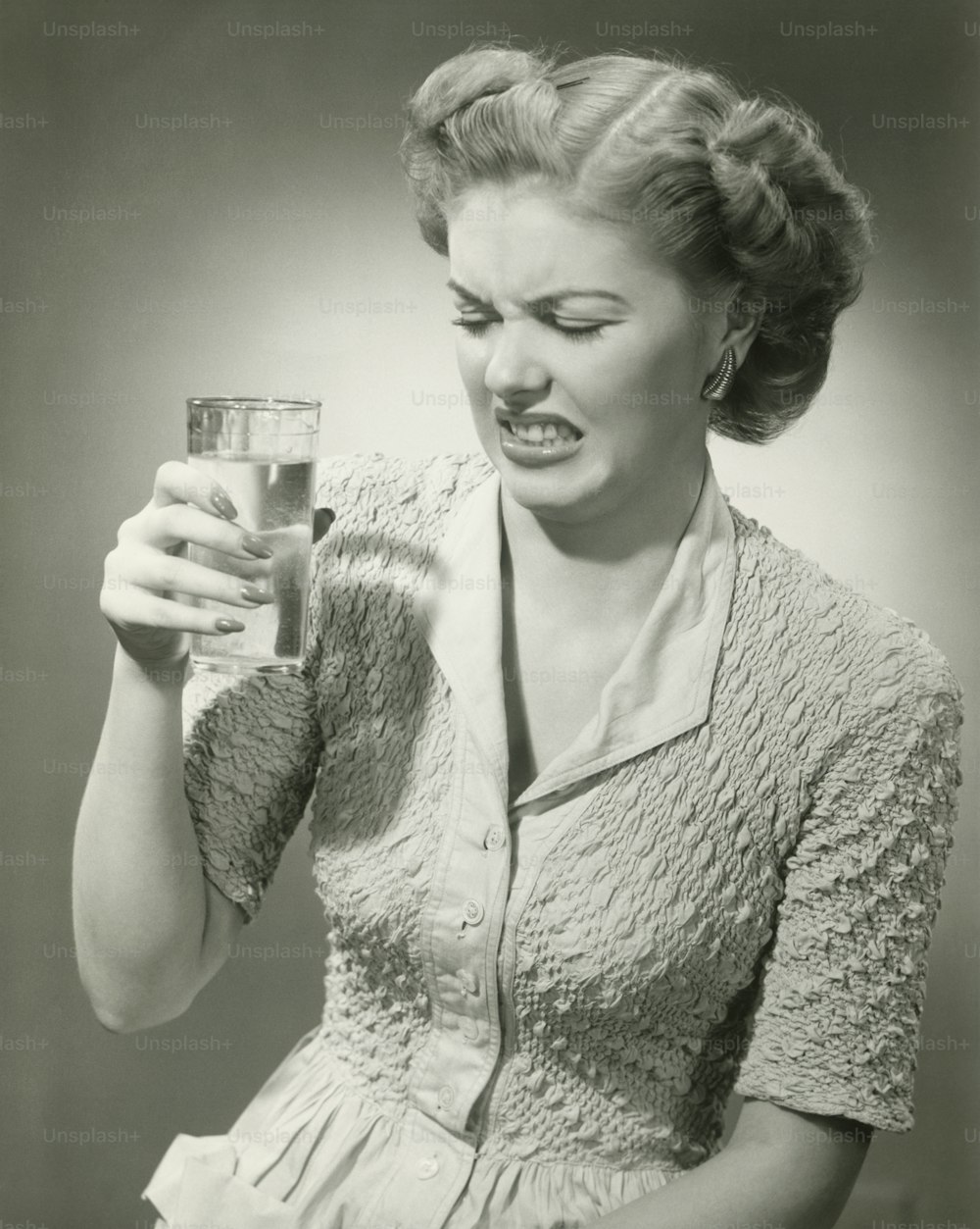 a woman holding a glass of water in her hand