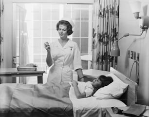 a black and white photo of a nurse and a child in a hospital bed