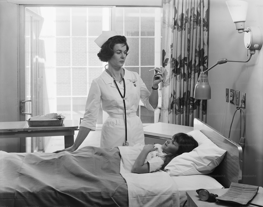 a nurse standing next to a little girl in a hospital bed