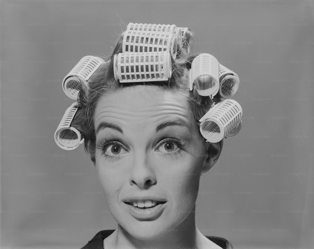 Una foto in bianco e nero di una donna con rulli di capelli in testa