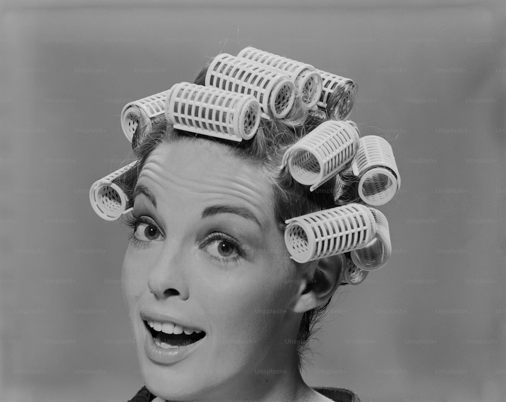 a black and white photo of a woman with curlers on her head