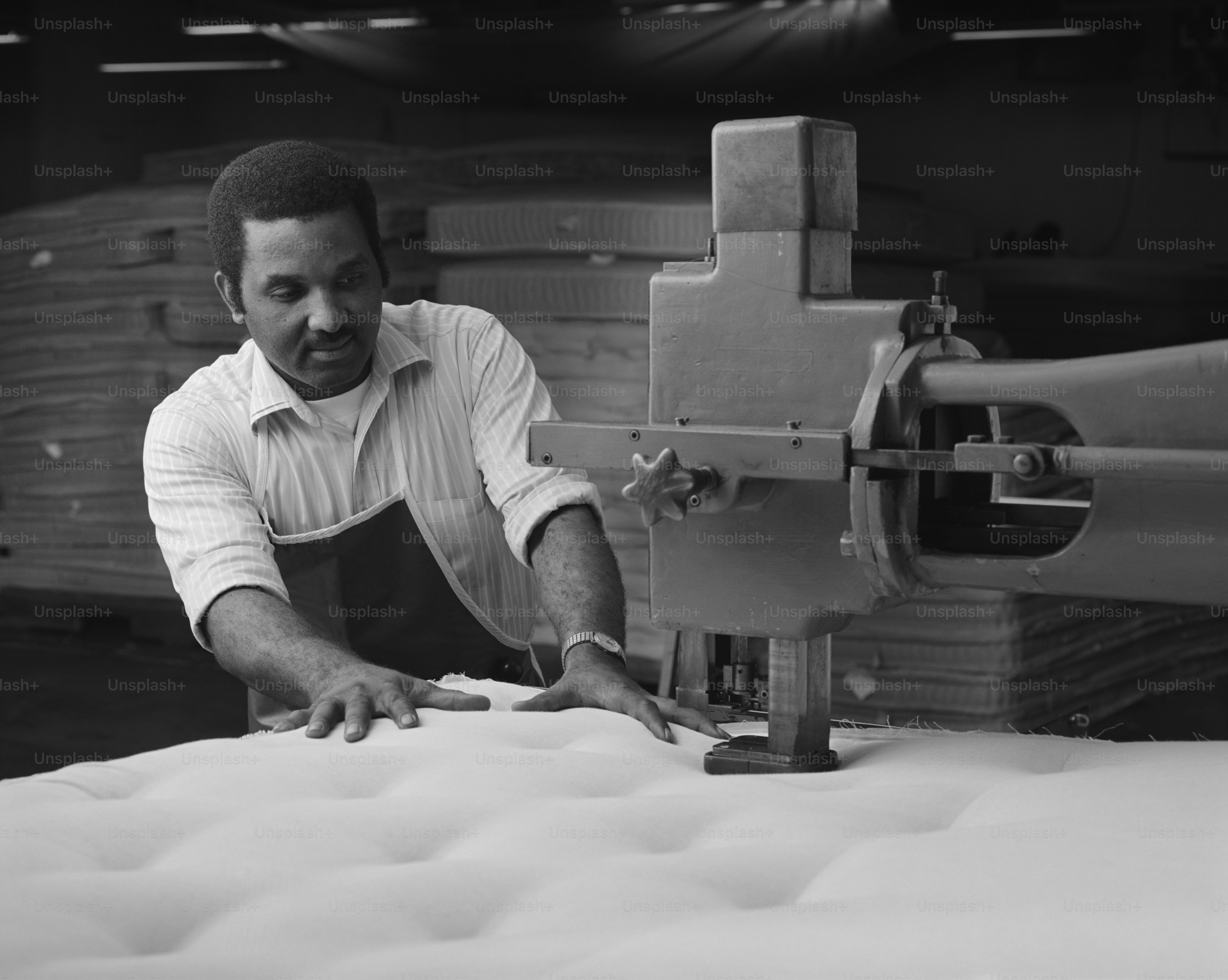 a man working on a mattress in a factory