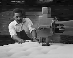 a man working on a mattress in a factory