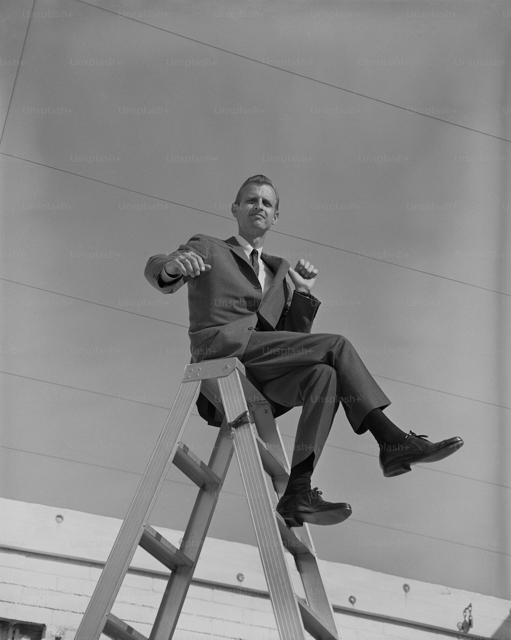 a man in a suit sitting on a ladder
