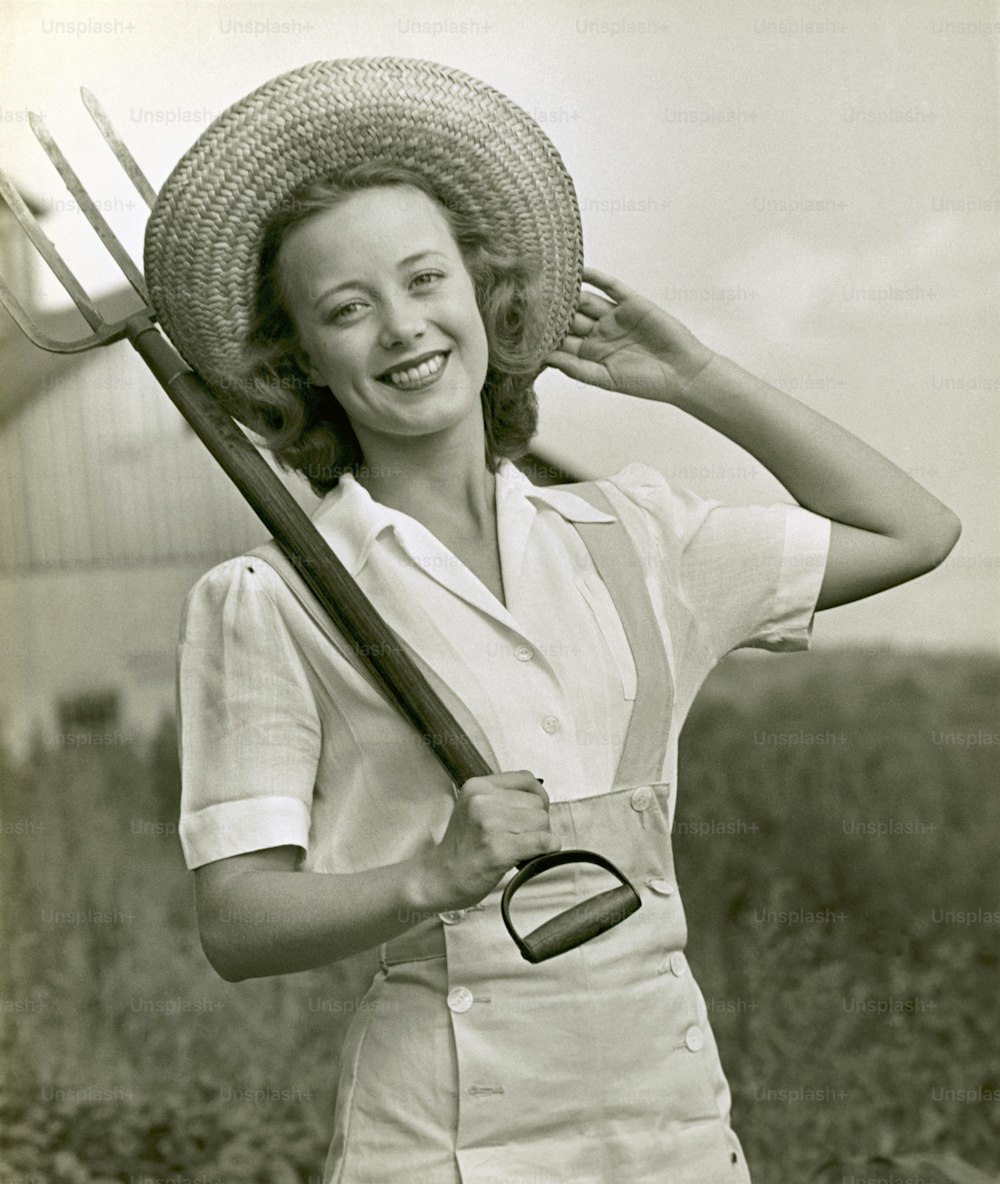 UNITED STATES - CIRCA 1950s:  Young farm woman with pitchfork.