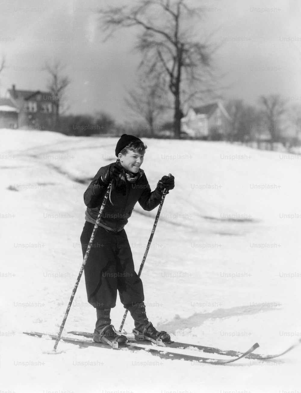 UNITED STATES - Circa 1930s:  Boy Standing Uneasily On Skis With Ski Poles Winter Hat Gloves Snow Learning.