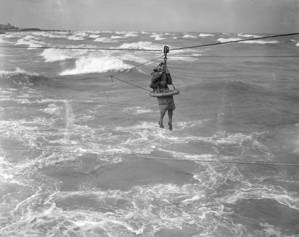 UNITED STATES - CIRCA 1940s: Woman Is Rescued From A Stranded Ship By Coast Guard, By Means Of A Breeches Buoy Which Travels On A Trolley From A Line Throwing Gun.