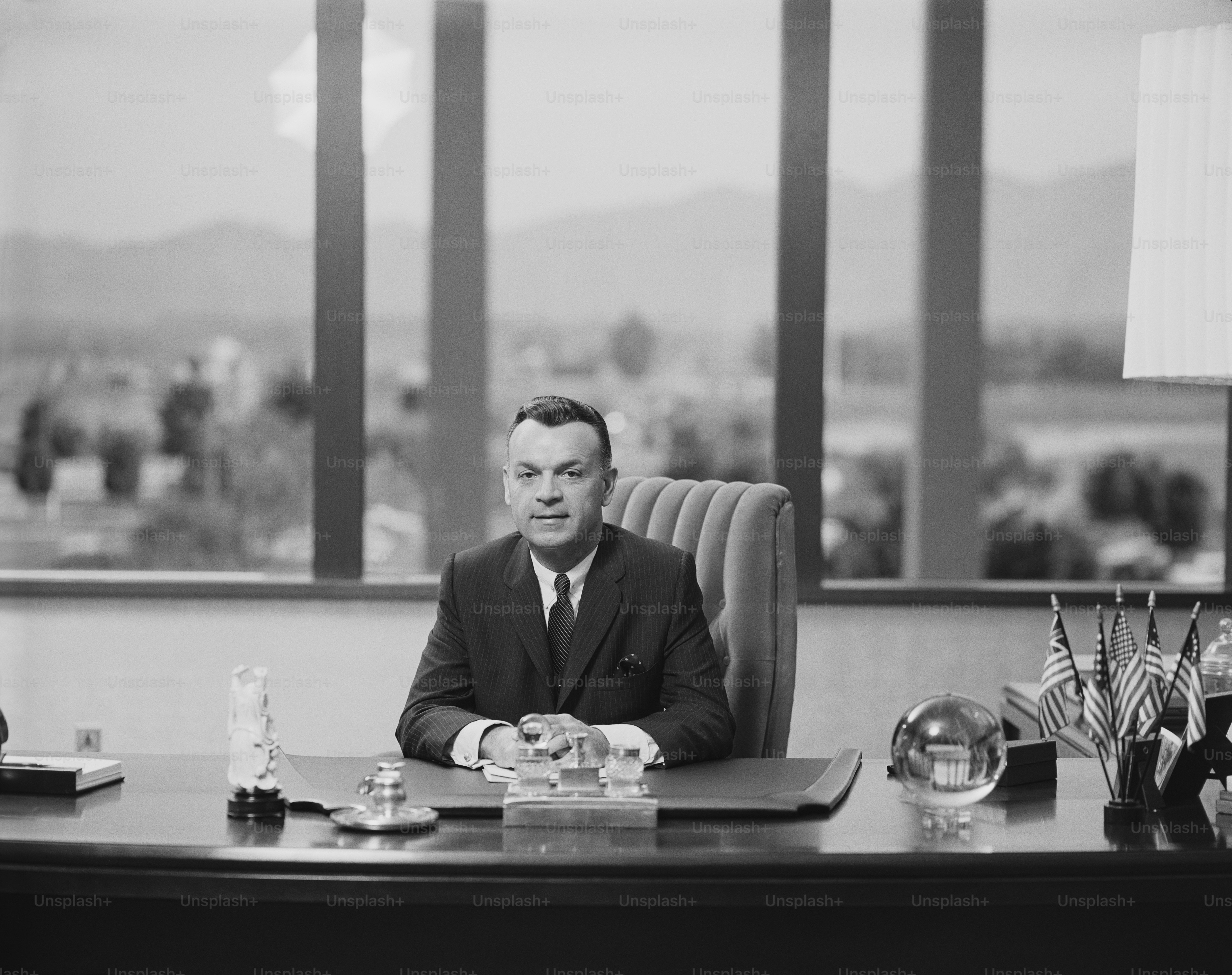 a black and white photo of a man sitting at a desk