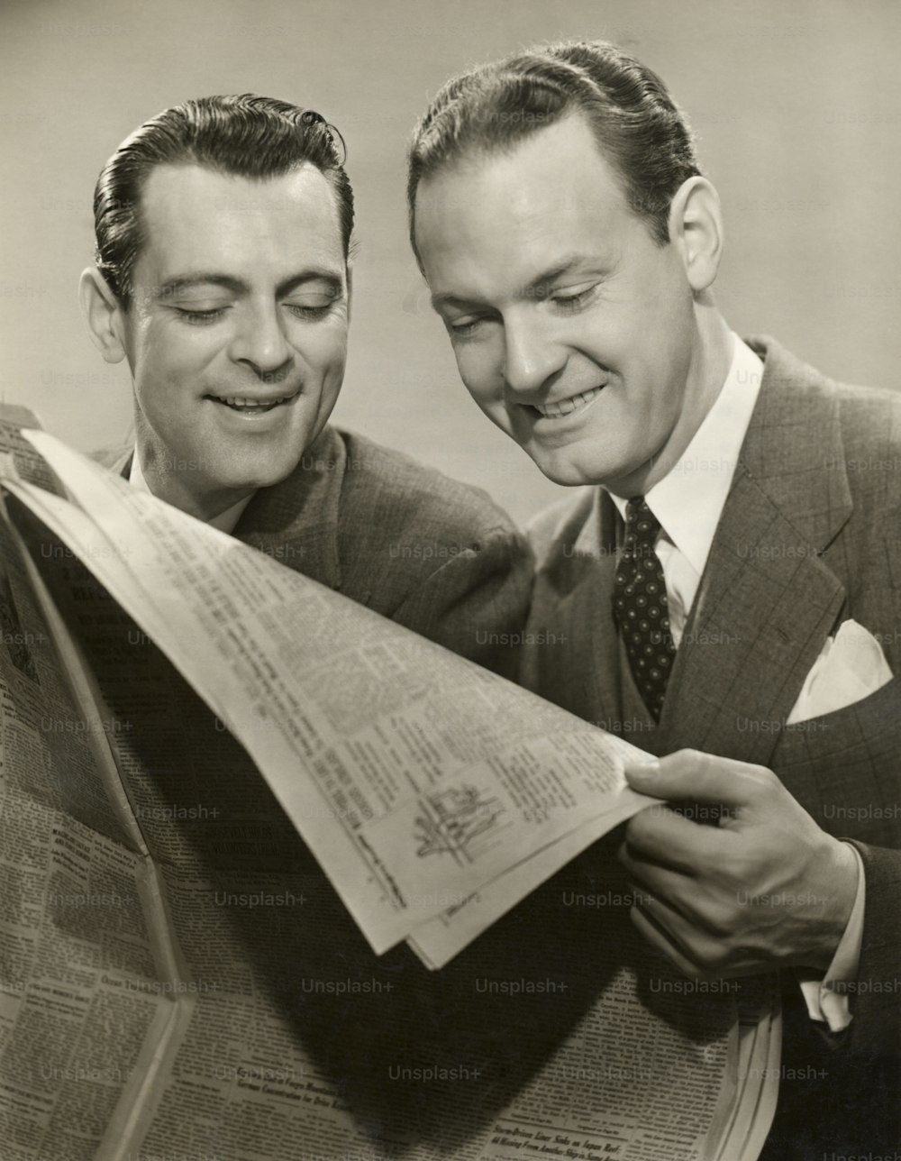 UNITED STATES - CIRCA 1950s:  Two men in suits reading newspaper.