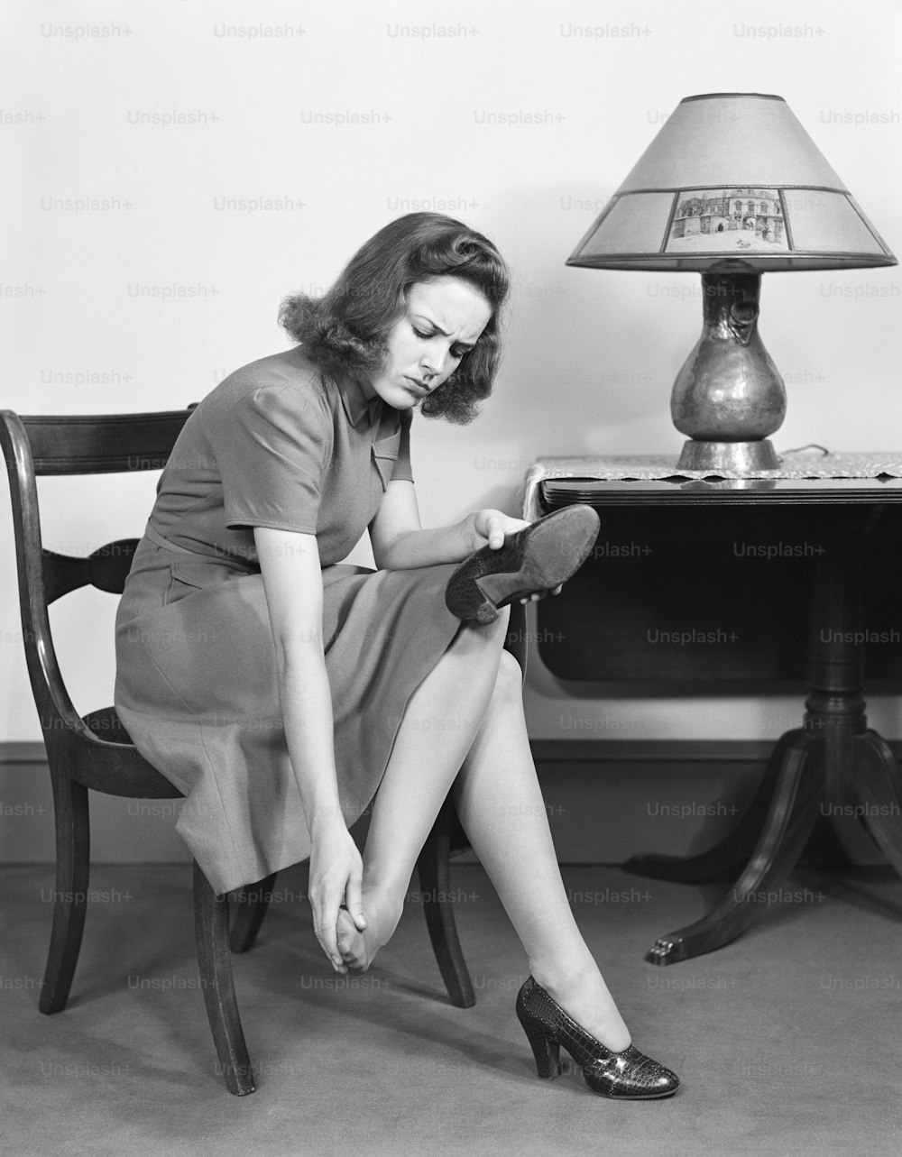 UNITED STATES - CIRCA 1950s:  Woman sitting in chair, rubbing her feet.