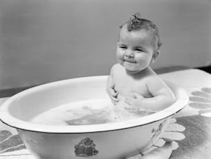 미국 - 1940년대경: 욕조에 앉아 웃고 있는 아기.