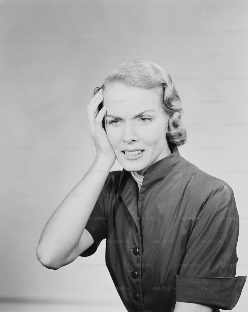 UNITED STATES - CIRCA 1950s:  Woman holding hand to her head, looking concerned.