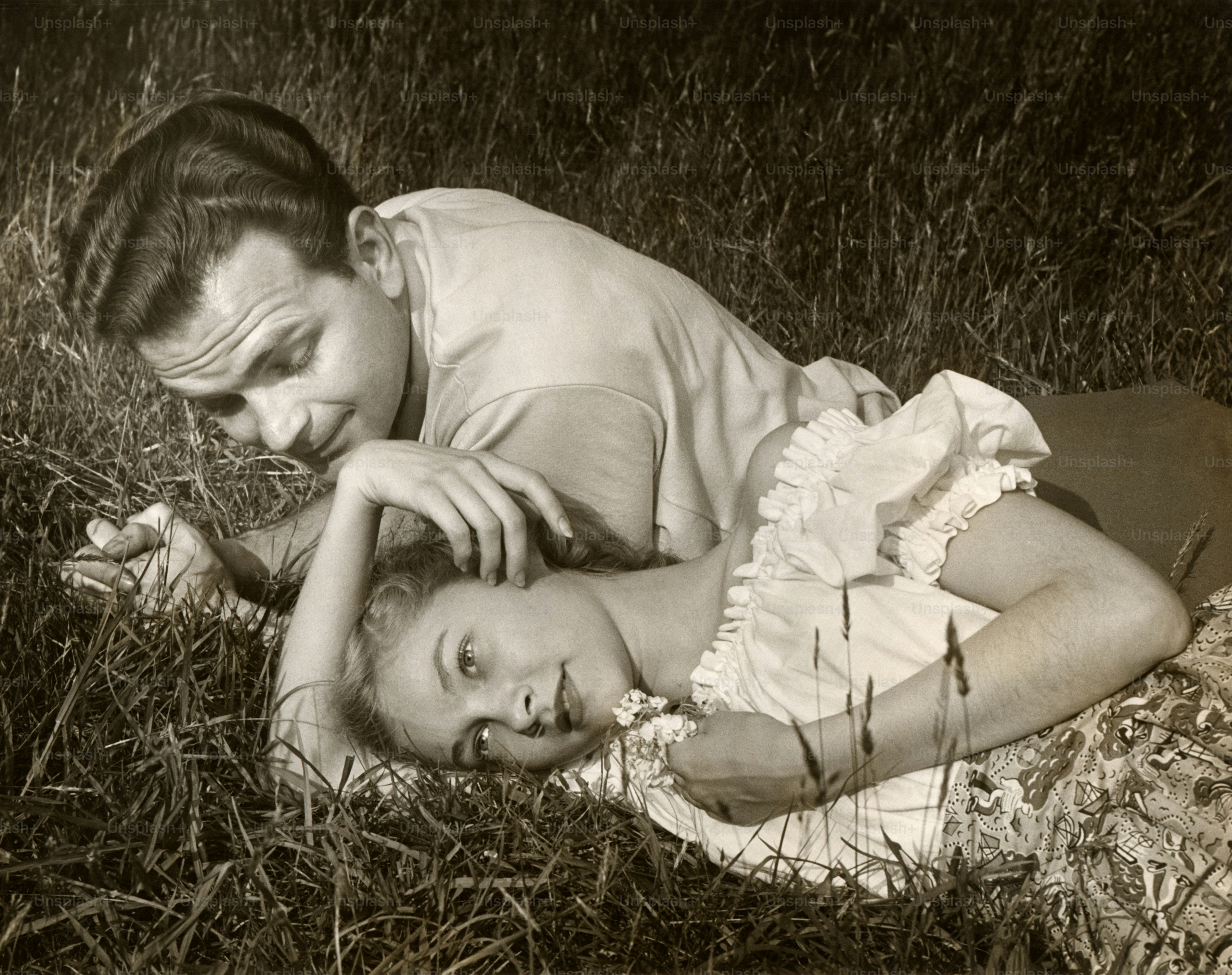 UNITED STATES - CIRCA 1950s:  Romantic couple outdoors on grass.