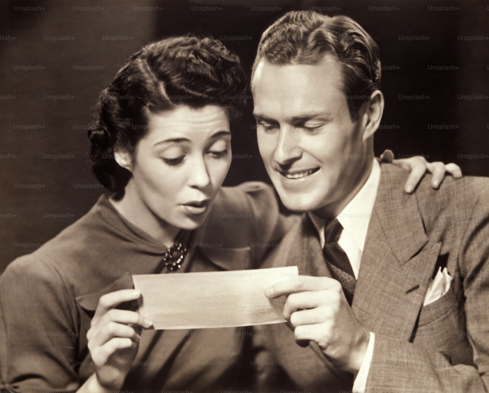UNITED STATES - CIRCA 1950s:  Couple looking at check.
