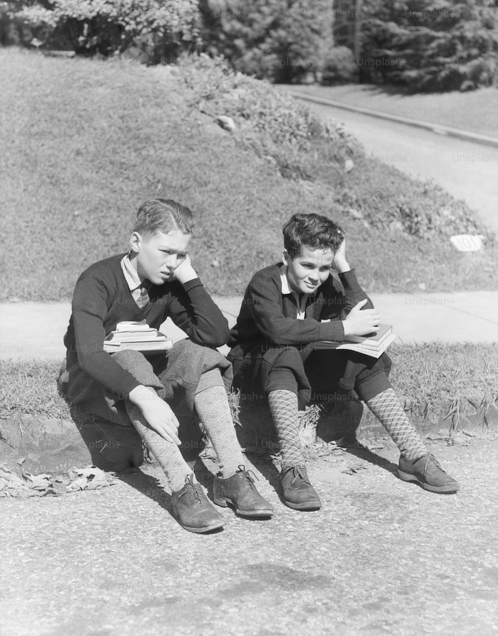 ESTADOS UNIDOS - POR VOLTA DE 1930: Dois estudantes com livros no colo, segurando cabeças nas mãos.