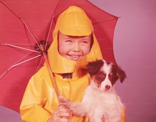 ÉTATS-UNIS - Circa 1960s : Garçon avec parapluie, tenant un chiot, souriant.