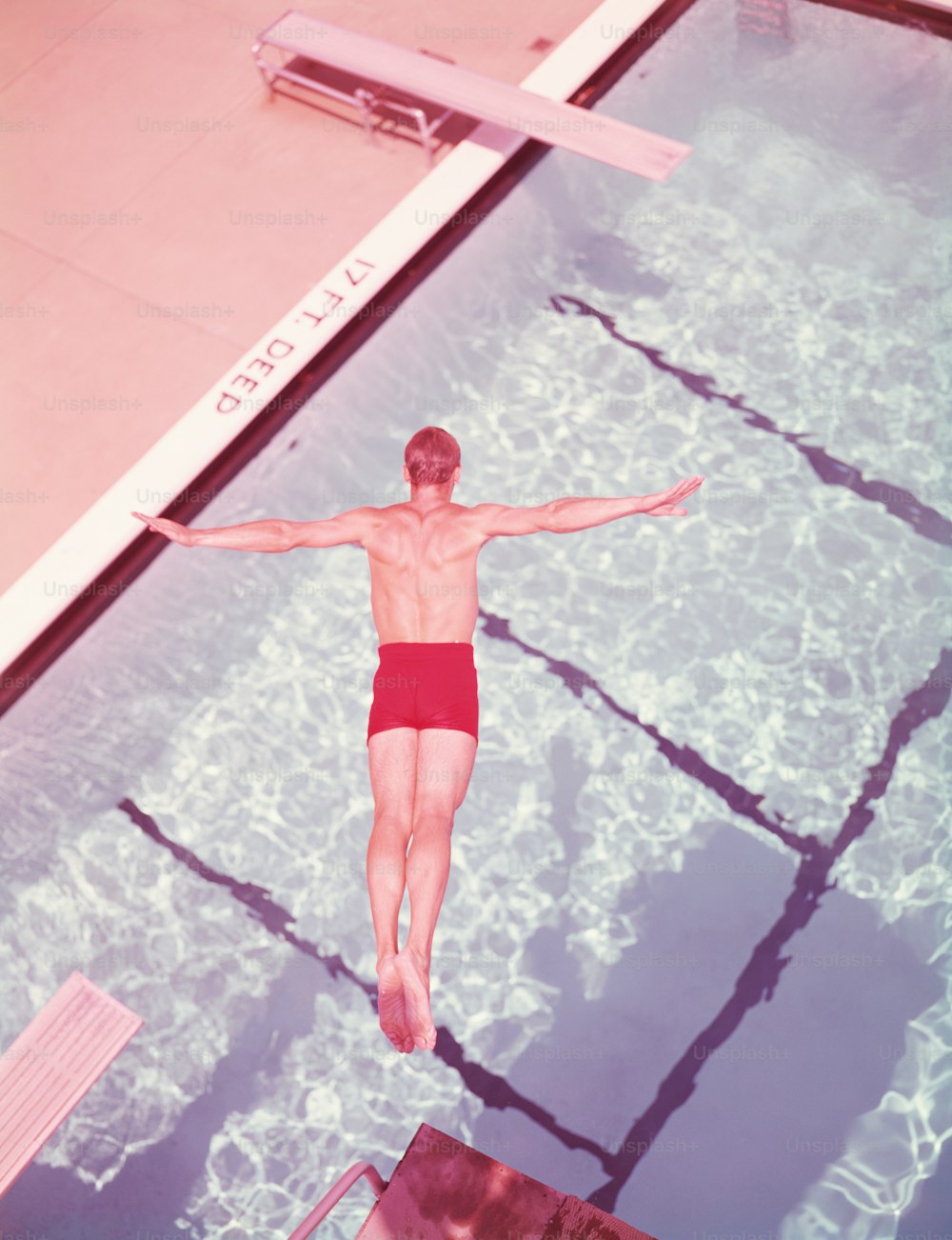 ESTADOS UNIDOS - POR VOLTA DE 1950: Homem mergulhando na piscina, vista aérea.